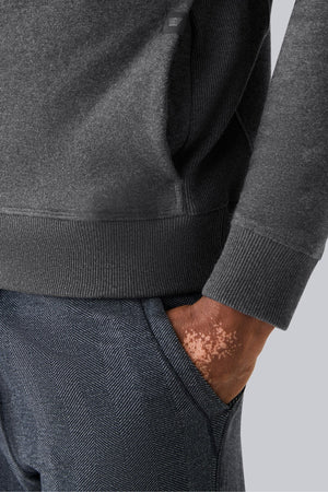 A person is shown from the back wearing the MACK WELDON - ACE HOODIE IN SHADOW HEATHER HERRINGBONE and gray pants, standing against a plain light gray background.