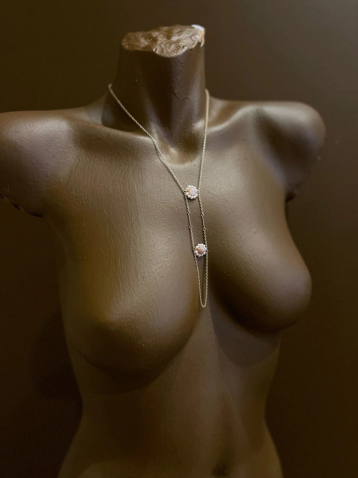 The GOLDISH - Floral Pink Moonstone and White Pearl Ladders to Bliss Necklace by GOLDISH is shown on a beige linen bust against a white background.