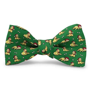 Add a touch of holiday cheer to your ensemble with the BIRD DOG BAY - SANTA PAWS SILK BOW TIE IN MID-GREEN. This playful, handmade bow tie by BIRD DOG BAY features a mid-green silk background adorned with a repeating pattern of yellow dogs wearing red hats, chewing on bones, and playing with balls—making it the perfect festive accessory for any holiday gathering.