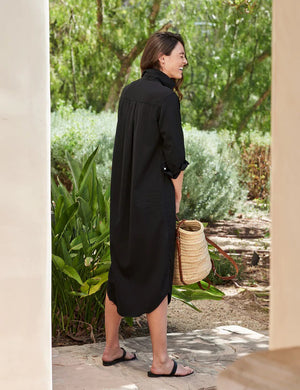 The dress is a FRANK & EILEEN RORY Maxi Shirtdress in Famous Denim Black. It has a collar, rolled-up sleeves, a single chest pocket on the left side, and a curved hem. Crafted from fine Italian cotton, it is displayed against a plain white textured background.