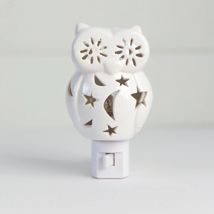 The OWL NIGHTLIGHT by LILY'S LIGHTS features a white ceramic owl design with cut-out star and moon patterns that allow light to shine through beautifully. Plugged into a white electrical base and set against a plain white background, this nightlight exemplifies quality craftsmanship, making it one of the most unique gifts.