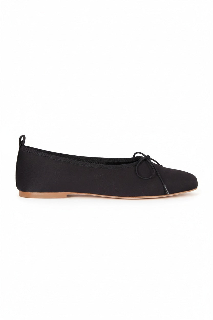 The AUGUSTA - SIENNA BALLET FLAT by AUGUSTA, handcrafted in Spain, showcases a silver finish with a front bow, low brown sole, and heel pull tab, displayed in side profile against a plain light background.