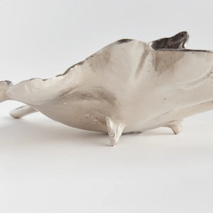 The NAPA HOME AND GARDEN - FOLIA DECORATIVE SILVER TRAY is a silver, leaf-shaped dish featuring detailed veins and a textured surface. It showcases natural leaf design with a stem on one end, offering an elegant silver finish.