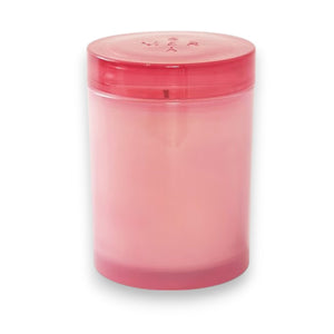 The MERSEA Cabana Flower Jolie Jar Candle features a pink cylindrical design in a translucent container with a matching lid, infused with soothing Ylang Ylang, and shown against a white background.