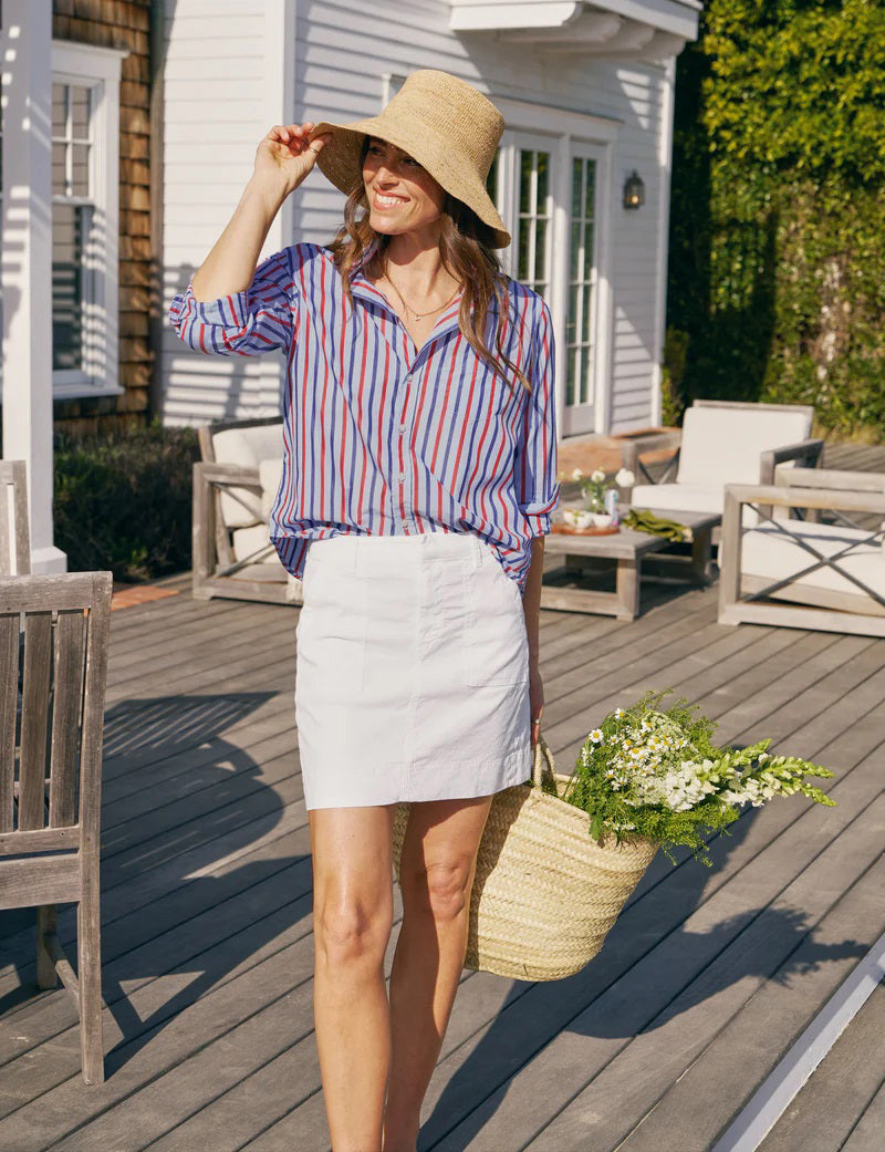 A woman smiles in sunlight while wearing the FRANK &amp; EILEEN EILEEN Relaxed Button Up Shirt in Superluxe Cotton Stripe, accessorized with gold rings and a delicate necklace.
