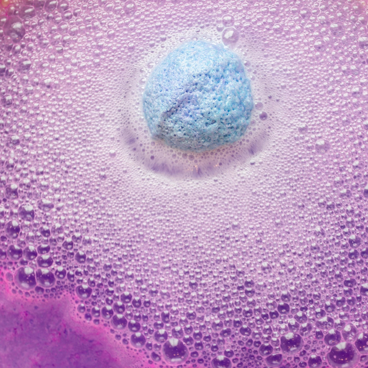 Instructional graphic with text on how to use the MUSEE - DREAMWEAVER THERAPY BATH BALM by MUSEE, featuring a dissolving colorful bath balm in pink bubbly water within a white flower outline on a pink background.