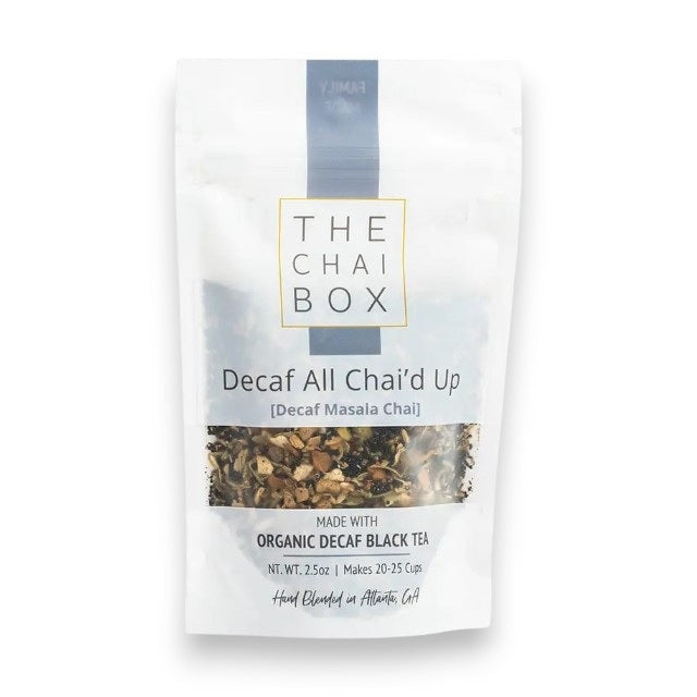 Back view of a white THE CHAI BOX package labeled “DECAF ALL CHAI’D UP,” displaying brewing instructions, a QR code, and ingredients. The packaging notes that it is gluten-free, vegan, and family made. This decaf masala chai from THE CHAI BOX blends aromatic spices with organic decaffeinated black tea for a comforting cup any time of day.