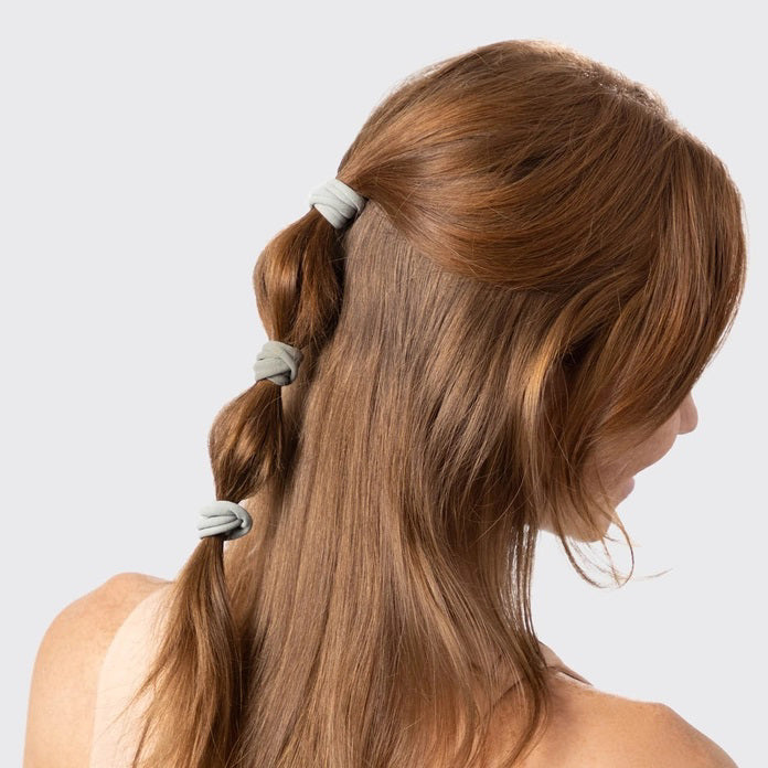 A KITSCH set of 20 eco-friendly nylon elastics in muted green, made from recycled materials. These essential hair ties come packaged under the "KITSCH" brand, displayed on hanging packaging with brand and product details.