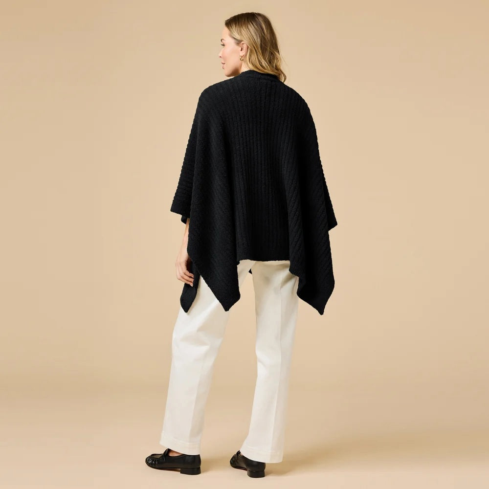 A woman wearing a black SOFTIES - SOLID RIB MARSHMALLOW SHAWL over a grey top and white trousers.