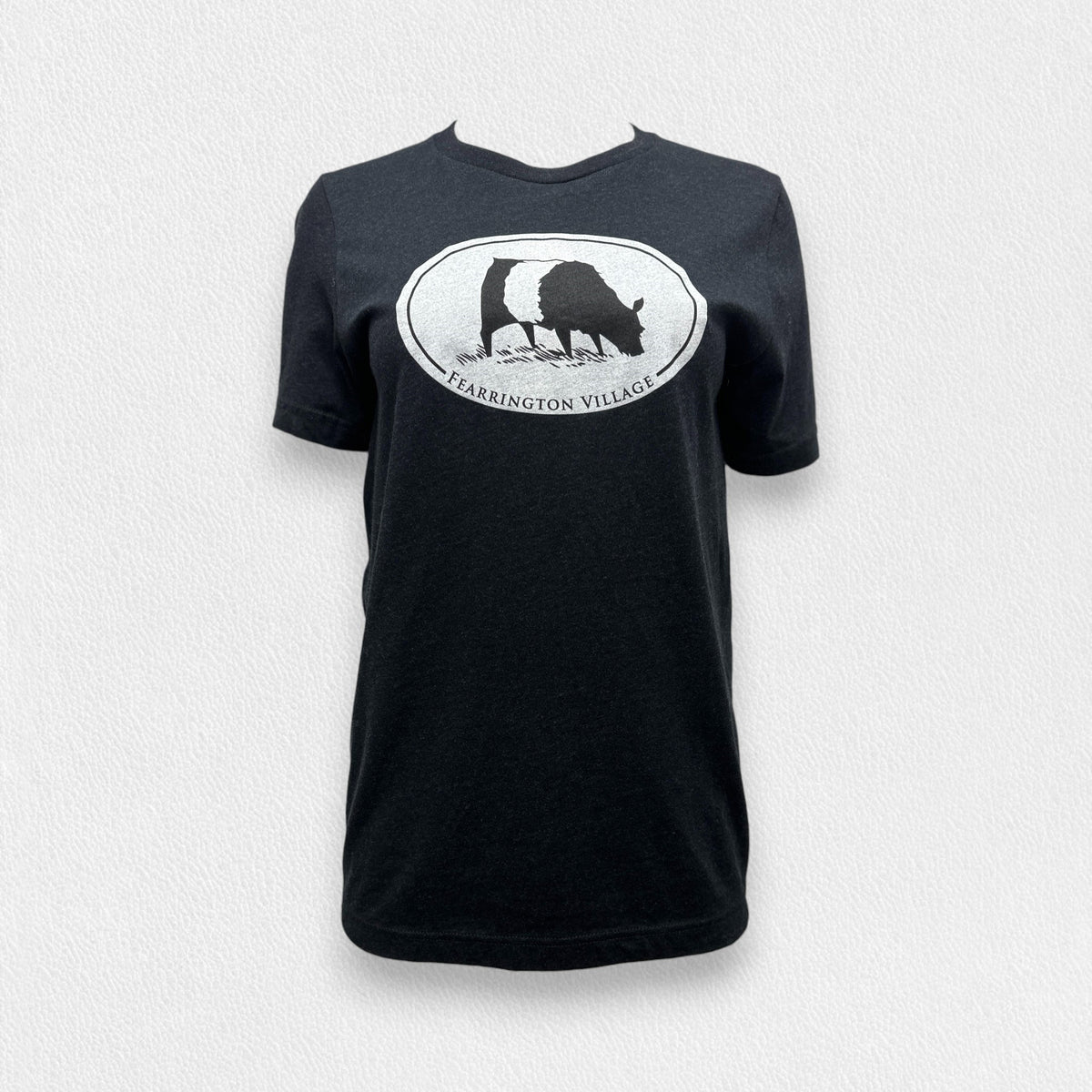 A black triblend unisex tee from the FEARRINGTON LIFESTYLE COLLECTION by GILDAN, showcasing a white oval logo with a silhouette of a goat and the text &quot;FEARRINGTON VILLAGE&quot; underneath, set against a plain light gray background.