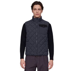 A person stands facing forward, wearing the SAVE THE DUCK - FABRICE Puffer Vest in Blue Black from SAVE THE DUCK, featuring recycled Plumtech insulation, layered over a black long-sleeve shirt and gray pants. They have a neutral facial expression and are posed against a plain white background.