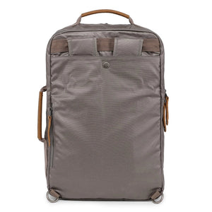 A close-up of the TSD BRAND - MADRONE Coated Canvas Backpack in Grey shows its brown leather accents and an unzipped front pocket with a black wallet partially visible inside.