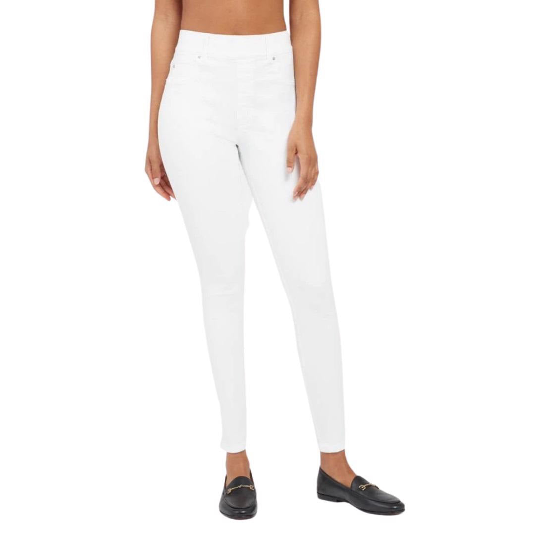 A person wearing the SPANX - SKINNY JEAN, which is a pair of high-waisted white skinny jeans crafted from stretch denim, and black loafers stands against a plain white background. The image focuses on the lower body, highlighting the jeans&#39; high-rise coverage and footwear.