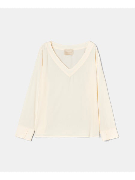 The MOMONI - TERENCE V NECK TOP is a light cream-colored long-sleeve blouse with a V-neckline. Made from soft and flowy silk crepe, the blouse features a simple design with straight sleeves ending in slightly wide cuffs against a plain white background.