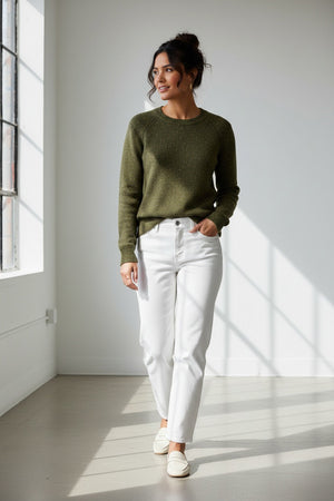 A person wearing the HINSON WU Queenie Long Sleeve Sequin Sweater in Oregano—an everyday essential crafted from breathable cotton with subtle sequin embellishments—paired with gold hoop earrings and touching their collar with one hand.