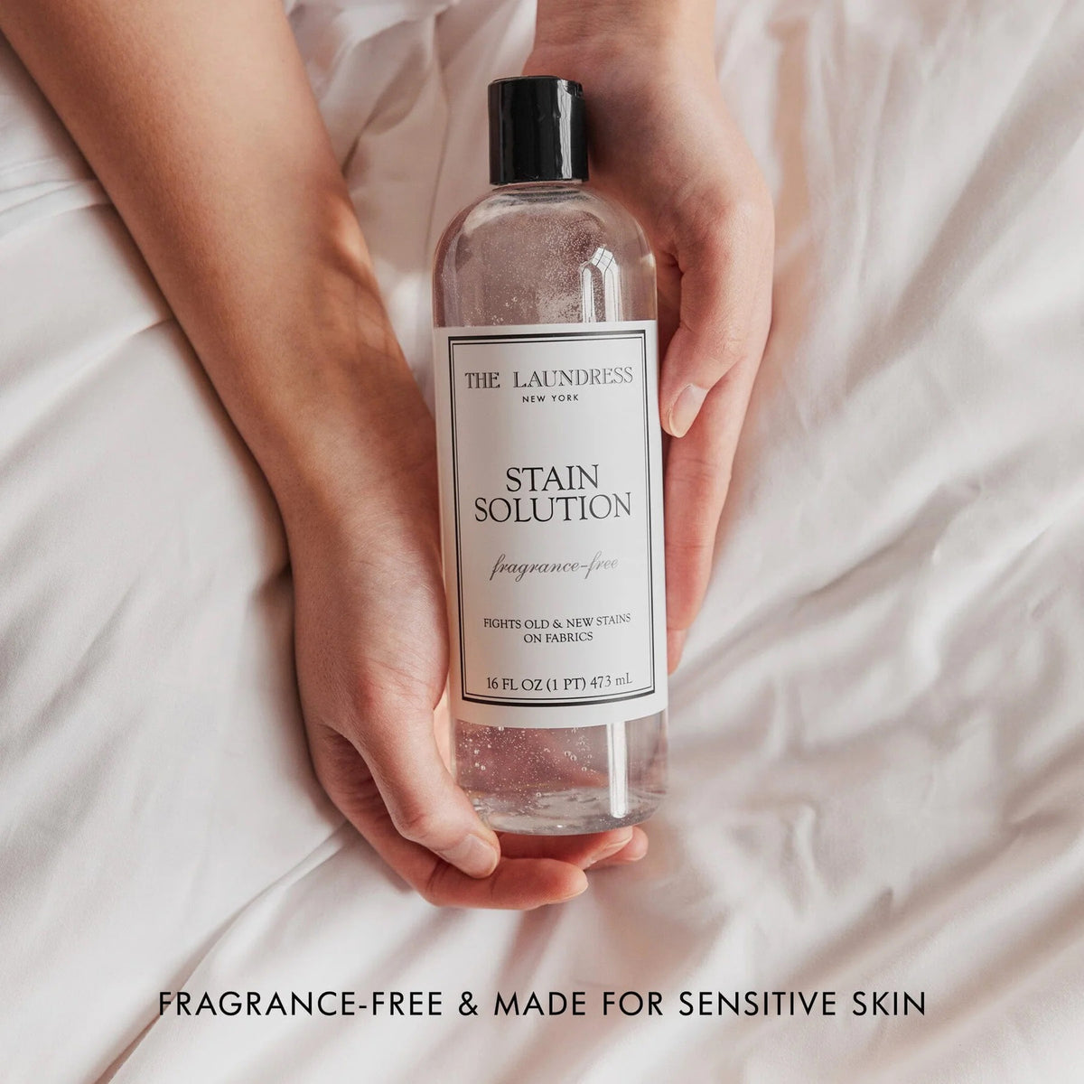 A bottle of THE LAUNDRESS - STAIN SOLUTION 16OZ is shown against a light background. The label reads &quot;The Laundress New York, Stain Solution, fragrance-free, Fights old &amp; new stains on fabrics.&quot; This powerful unscented solution comes in a 16 fl. oz. (1 pint) or 473 mL bottle.