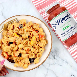 A jar of YO MAMA'S - BELLISIMA BASIL SAUCE from YO MAMA'S FOODS. The label emphasizes fresh ingredients, all-natural goodness, keto certification, no added sugar, and low sodium. Net weight: 25 oz (708 g).