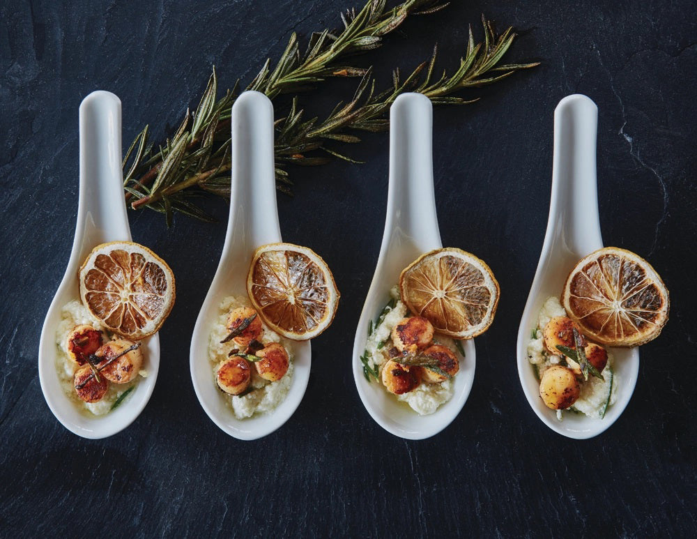 A transparent, tall bag containing neatly stacked dried orange slices. The bag is tied at the top with a clear ribbon. The product label reads "DARDIMANS - CRISPY ORANGE SLICES," hinting at the fresh orange flavor packed with vitamin C. The background is a light textured surface, giving a rustic appearance.