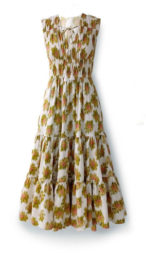 A woman stands against a plain light background wearing the HOPE FOR FLOWERS Tiered Peasant Maxi Dress in Pink Warped Ikat, a sleeveless, ankle-length dress with a shirred bodice and tiered skirt. She completes the look with brown sandals.