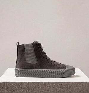 The DANIELLA LEHAVI - OSAKA HIGH TOP SNEAKER by DANIELLA LEHAVI features gray suede uppers and ribbed rubber soles, shown on a white pedestal against a plain light background. These stylish high-tops perfectly combine everyday comfort with modern style.