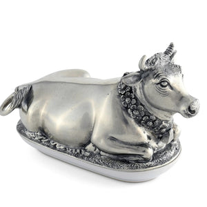 The VAGABOND HOUSE Mabel Cow Butter Dish, by VAGABOND HOUSE, is a silver-toned luxury pewter piece with intricate details. The cow’s textured features and elegant oval base highlight its exquisite craftsmanship.