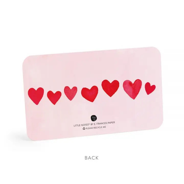 The E. FRANCES - LITTLE NOTES BLUSH MINI HEARTS is a rectangular mini note card with a light pink background and red hearts in various sizes. "Little Notes® by E. FRANCES PAPER" and "Please recycle me." are printed at the bottom.