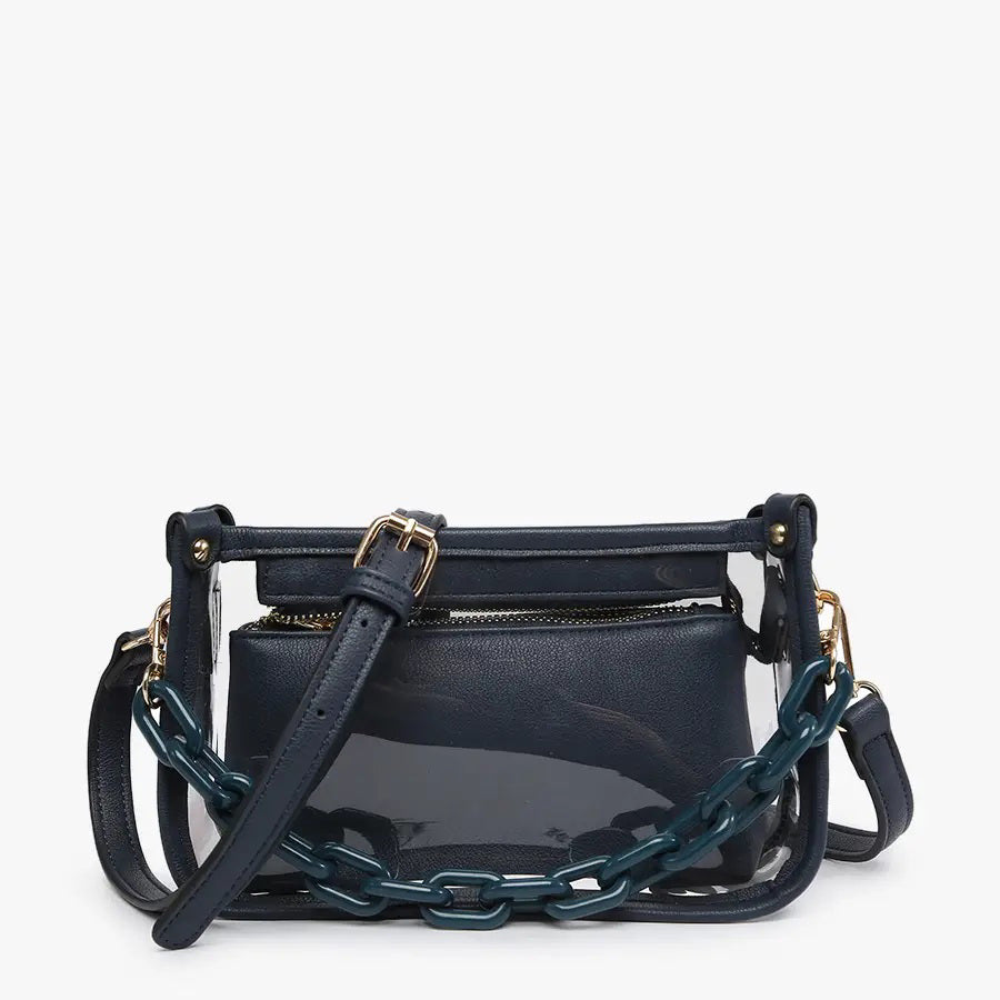 Introducing the CLEAR CROSSBODY BAG by JEN &amp; CO: A stylish handbag crafted from vegan leather, showcasing a layered beige design with an open top and a visible zipper pocket. This bag is elegantly framed by a transparent outer layer and is complemented by a chunky beige chain strap for additional style and versatility.