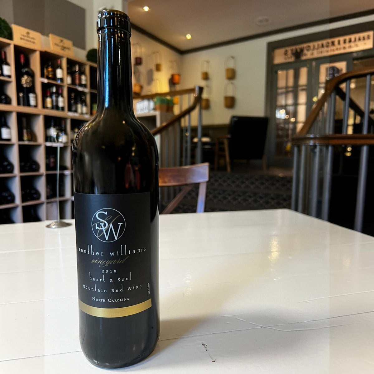 A dark glass wine bottle labeled “Souther Williams ‘Heart and Soul’ 2018” from WINE: SOUTHER WILLIAMS, featuring a black and gold label, crafted in the Blue Ridge Mountains and reflecting the unique character of North Carolina red wine.
