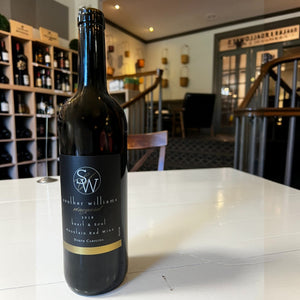 A dark glass wine bottle labeled “Souther Williams ‘Heart and Soul’ 2018” from WINE: SOUTHER WILLIAMS, featuring a black and gold label, crafted in the Blue Ridge Mountains and reflecting the unique character of North Carolina red wine.