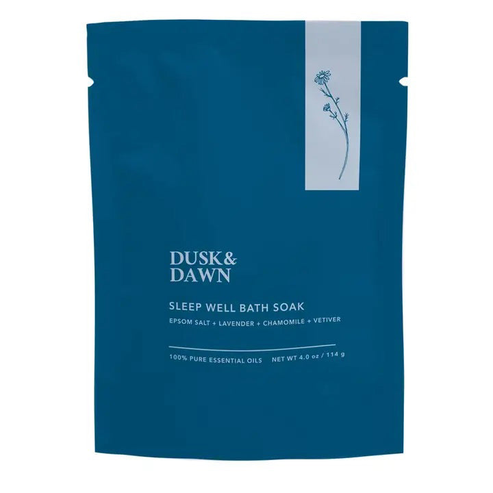 A blue packet labeled "GIFTEN MARKET Sleep Well Bath Soak - Epsom Salt and Lavender" contains Epsom salt, organic lavender, chamomile, and vetiver. The design features a minimalist floral illustration and states a net weight of 4.0 oz (114 g) along with "100% Pure Essential Oils" for a soothing bath soak experience.