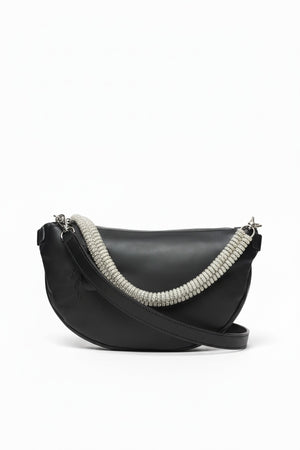 The GANRIELE FRANTZEN - SCARAB LEATHER XL BELT BAG IN BLACK WITH EXTRA CRYSTAL STRAP by GABRIELE FRANTZEN is a black leather, crescent-shaped crossbody bag featuring a long black strap and an extra decorative crystal handle, displayed against a plain white background.