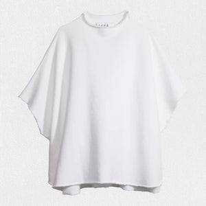 Displayed against a textured white background, the FRANK AND EILEEN - AUDREY FUNNEL NECK CAPELET IN WHITE exudes sophistication with its loose-fitting, short-sleeved design. Featuring a high, round neckline and minimalist style, this capelet is made from 100% Cotton Fleece by the renowned brand FRANK & EILEEN, making it a refined addition to any wardrobe.