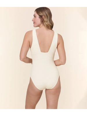 A woman models the ANDIE SWIM The Mykonos One Piece Swimsuit in Textured Wave Gardenia, standing against a plain light beige background.