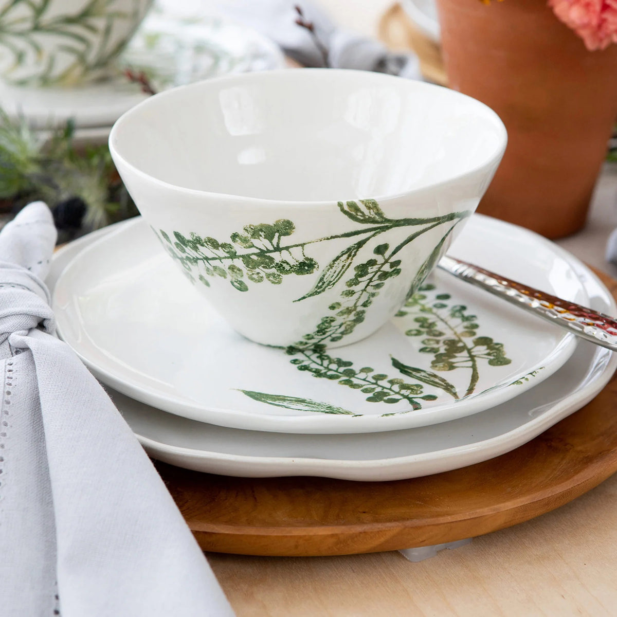 The VIETRI - Fauna Cereal Bowl is a small, white ceramic piece adorned with delicately painted green leaf designs on the exterior, evoking the lush greenery of Umbria. This bowl features a simple, elegant shape with a slightly flared rim and a smooth finish.