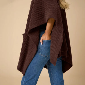A woman wearing a black SOFTIES - SOLID RIB MARSHMALLOW SHAWL over a grey top and white trousers.