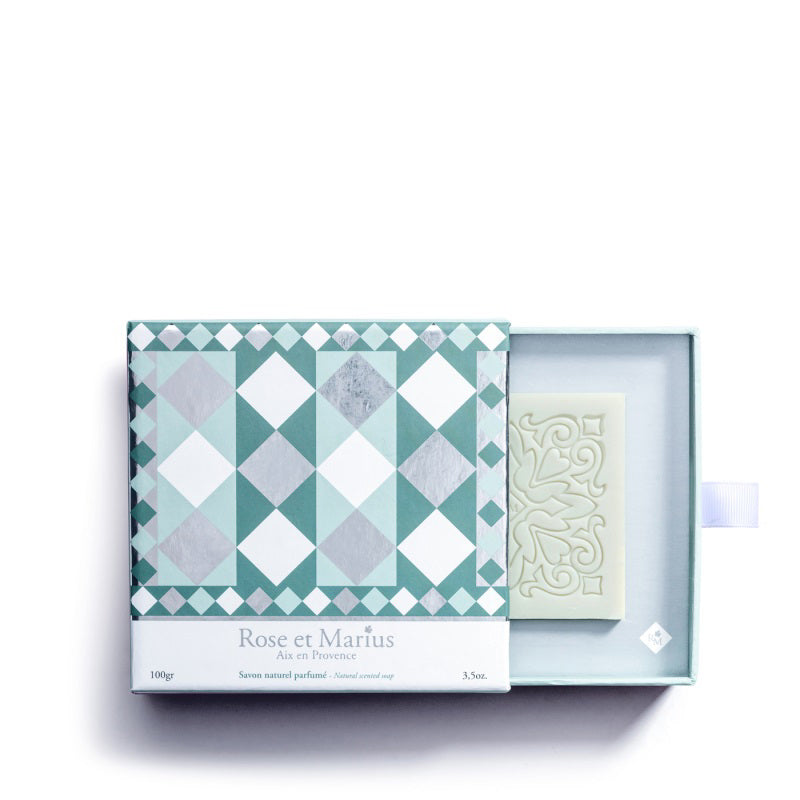 The ROSE ET MARIUS - WATER GARDEN SCENTED SOLID SOAP GIFT BOX features a decorative green and white diamond patterned box, partially open to reveal an ornate soap inspired by Provence, labeled with the ROSE ET MARIUS brand.