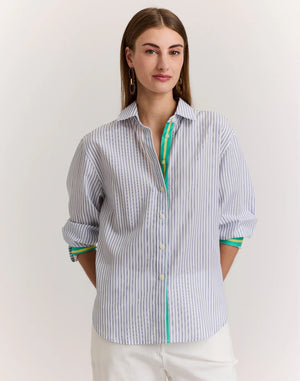A woman with straight brown hair is shown from behind wearing the HINSON WU JULIANA Long Sleeve Shirt in Contrast Stripe, a 100% cotton blue and white vertical striped shirt with back buttons and green-trimmed sleeves, against a light background.