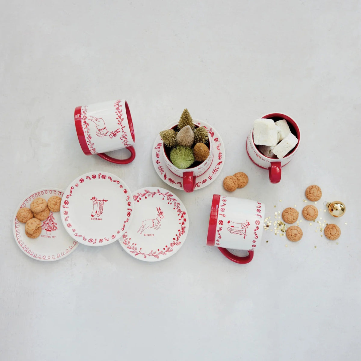 Creative Co-op stoneware mug with holiday design, red and white, featuring a white body with a red interior, base, and handle decorated with a red Christmas tree and string of lights pattern.