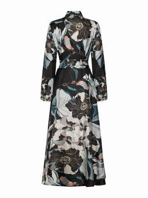 The FRANCO FERRARI ALOE Silk Maxi Shirtdress features long sleeves, an ankle-length cut, a black base with white, teal, and light pink oversized floral print, a collared neckline, and a matching tie belt at the waist.
