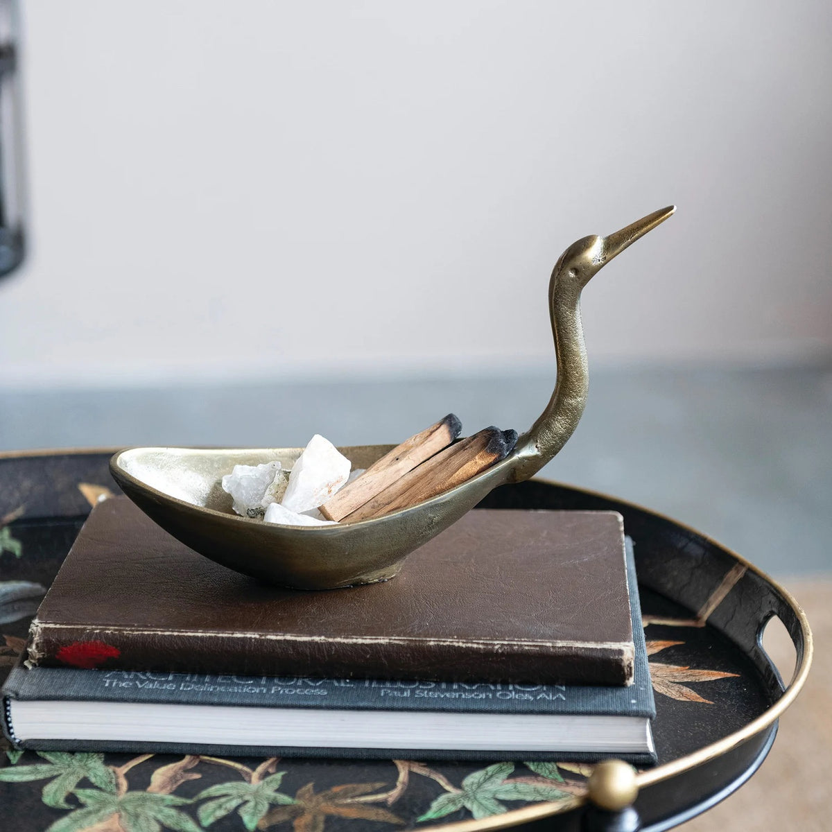 The CREATIVE COOP BIRD SHAPED BOWL IN ANTIQUE BRASS FINISH features a cast aluminum body with an elongated neck and beak, resembling a crane or heron for a stunning decorative accent.