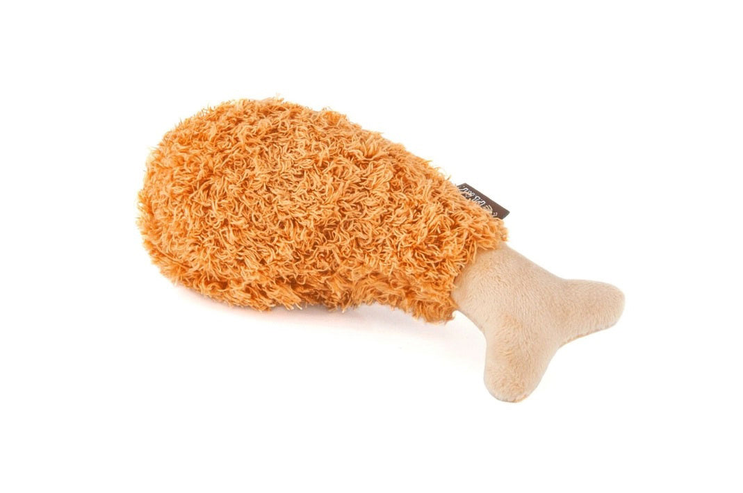 The AMERICAN CLASSIC FRIED CHICKEN plush toy by PLAY PET LIFESTYLE resembles a delectable drumstick, crafted with soft, fuzzy orange material for the meat and beige fabric for the bone - perfect for your little pup foodie.