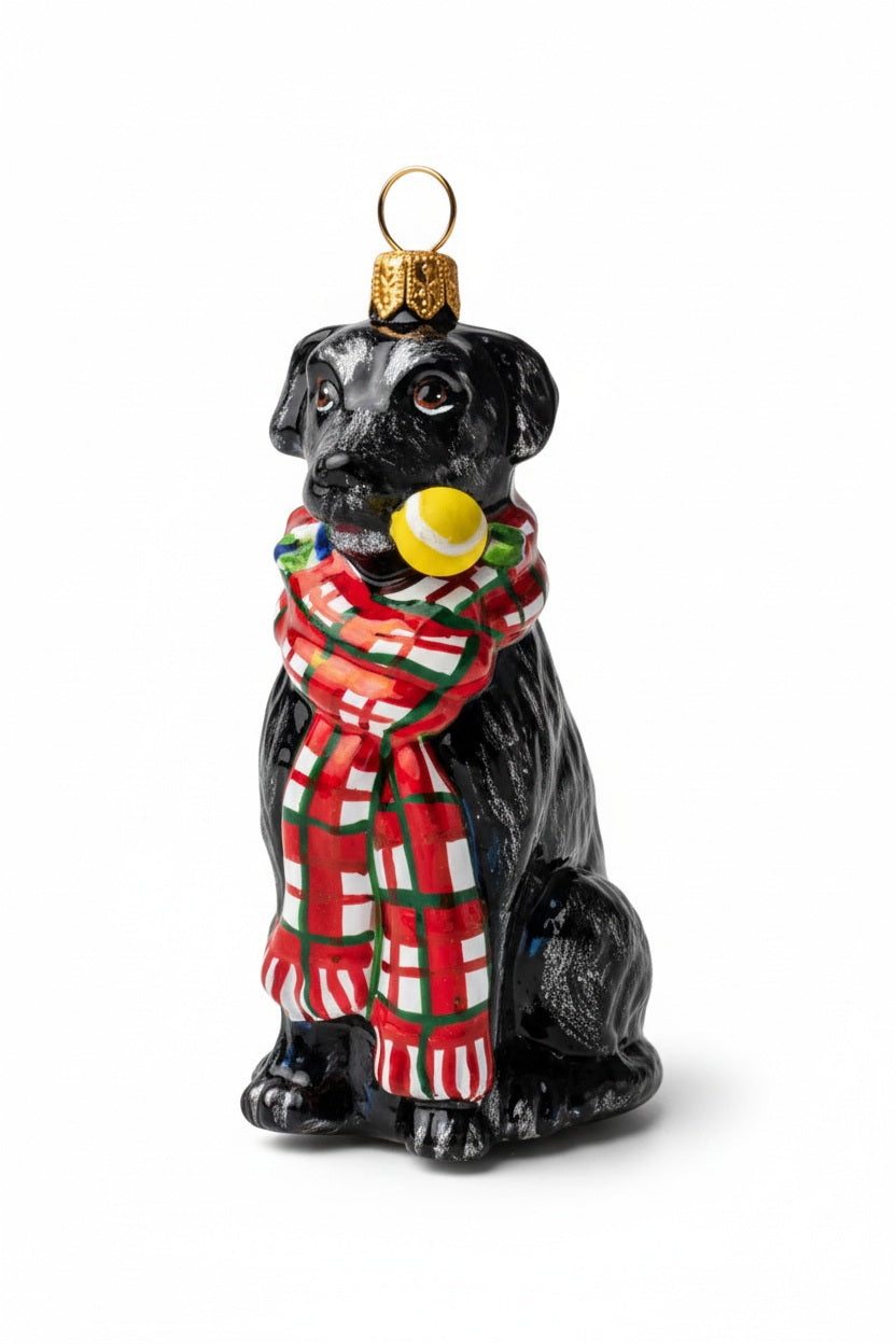 A JOY TO THE WORLD COLLECTIBLES BLACK LAB ORNAMENT featuring a handmade glass black Labrador wearing a red and green plaid scarf and holding a yellow tennis ball in its mouth.