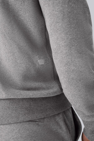 The MACK WELDON Ace Crew Neck Sweatshirt in Ice Storm Heather features long sleeves, ribbed cuffs and hem, and a small triangular stitch at the neckline, shown laid flat on a light background.