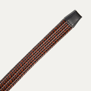 The WILL LEATHER GOODS - STRETCH BELT features a green, purple, and black braided design with full-grain leather accents by the silver buckle and tip, shown on a plain light background. Brand: WILL LEATHER GOODS.