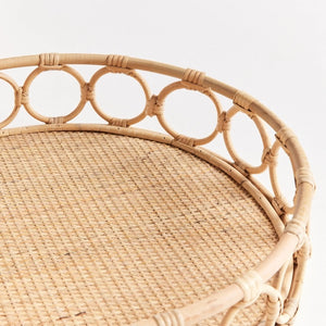 A close-up of the NAPA HOME AND GARDEN Ninette Rattan Round Tray, Small, in light brown with a woven base and decorative interlocking circular rim—ideal for boho decor—set against a plain white background.
