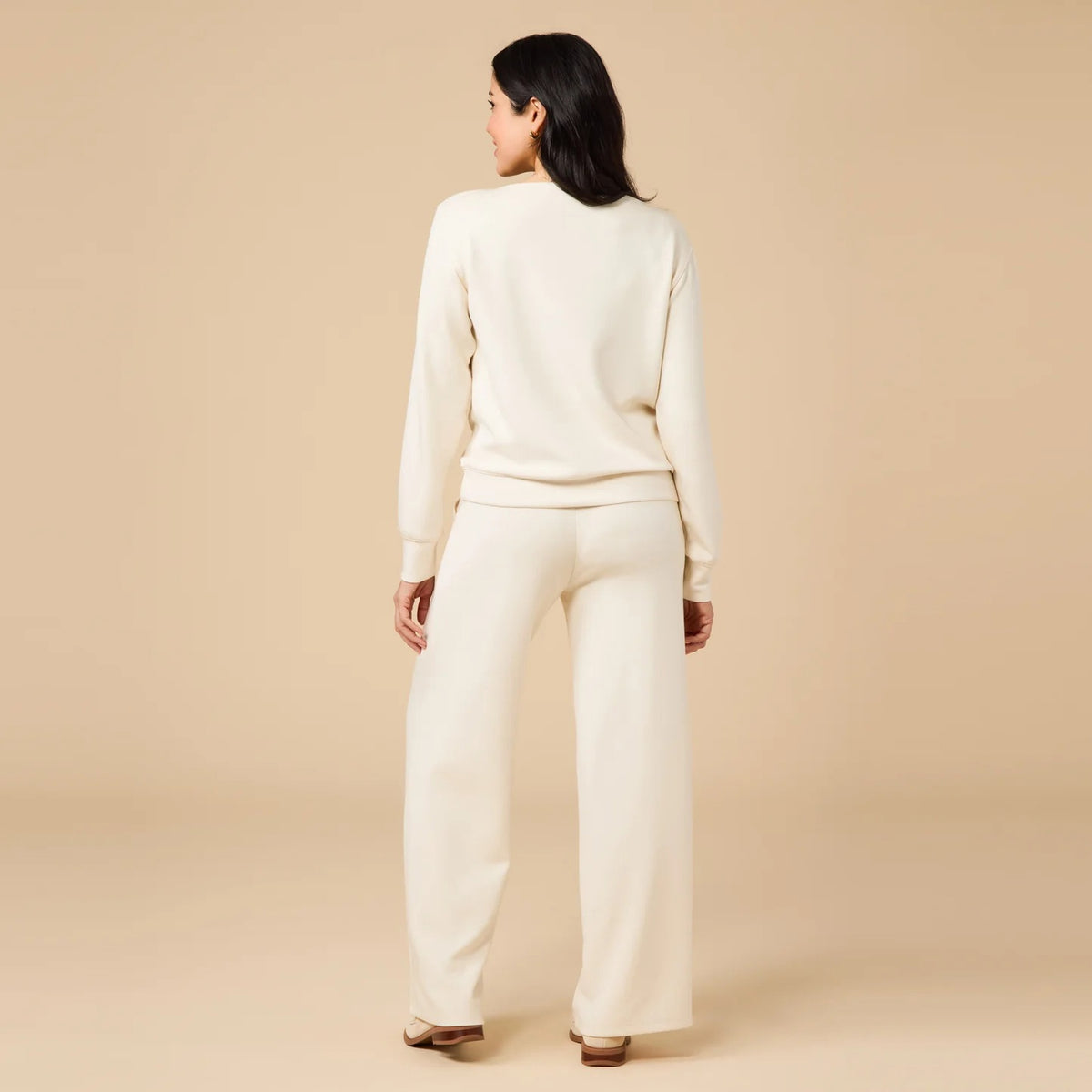 A woman wears a SOFTIES - DREAMTECH BOAT NECK WITH PINTUCK PANT SET in olive green, featuring a long-sleeve boat neck top and matching wide-leg pintuck pants.