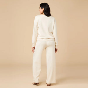 A woman wears a SOFTIES - DREAMTECH BOAT NECK WITH PINTUCK PANT SET in olive green, featuring a long-sleeve boat neck top and matching wide-leg pintuck pants.