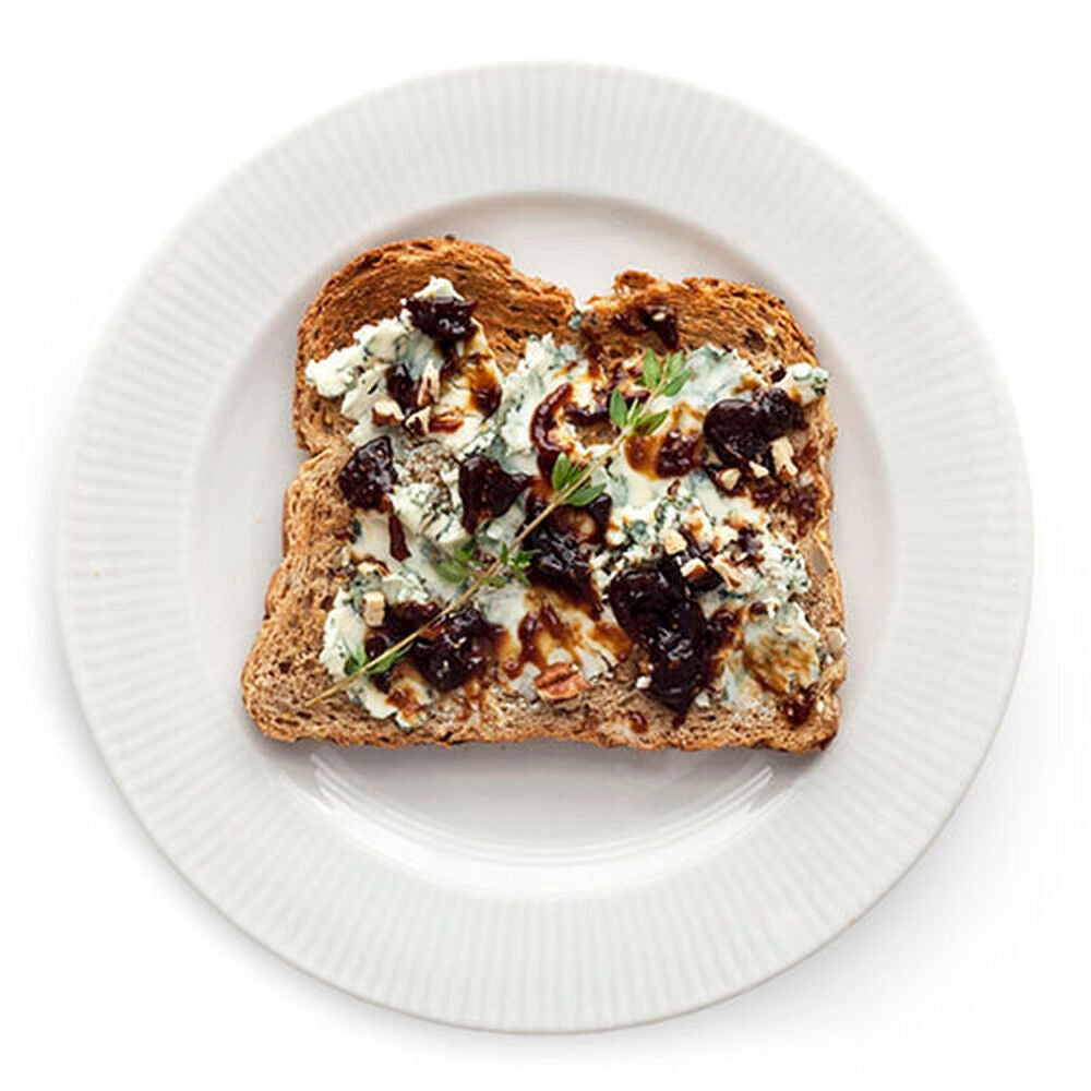 A glass jar of STONEWALL KITCHEN - FIG AND GINGER JAM, featuring a green lid and a white label with product details—ideal for spreading on breakfast breads or infusing marinades and glazes with a sweet-savory flavor.