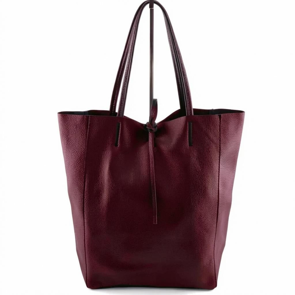 Introducing the LEATHER TOTE BAG IN DARK WINE by JIJOU CAPRI—a spacious Italian leather tote in a deep wine hue, designed with two strong handles and a convenient drawstring closure, ideal for carrying your daily essentials. Shown against a plain white background.