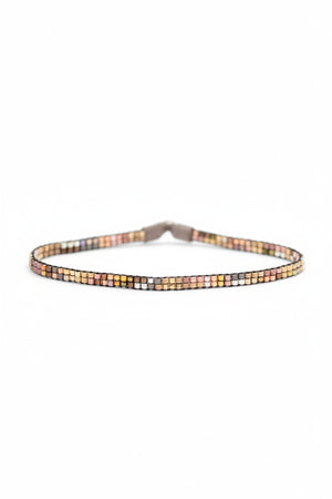 The JULIE ROFMAN - MINI BRACELET by JULIE ROFMAN JEWELRY is a vibrant handwoven piece adorned with small, square beads in various shades of pink, red, and white. It is displayed against a white background and includes a straightforward sterling silver clasp for convenient fastening.